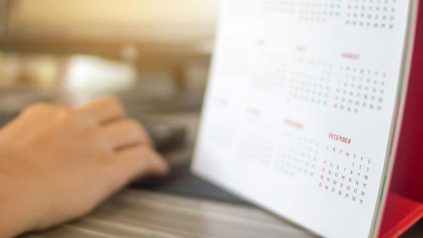 ایک ہاتھ کیلنڈر کے ساتھ، جنوری سے دھندلے مهینے، دسمبر واضح طور پر نظر آ رہا ہے۔