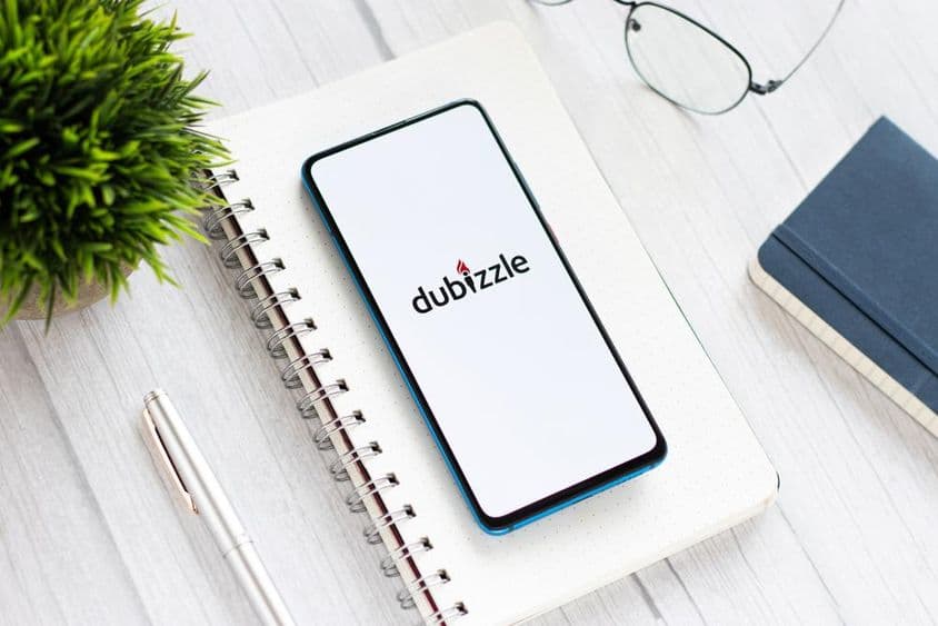 ایک ٹیبل پر بلاک پیڈ کے نیچے، چشمے اور ایک چھوٹے سبز پودے کے ساتھ، چلتی ہوئی دبیزل فون ایپ