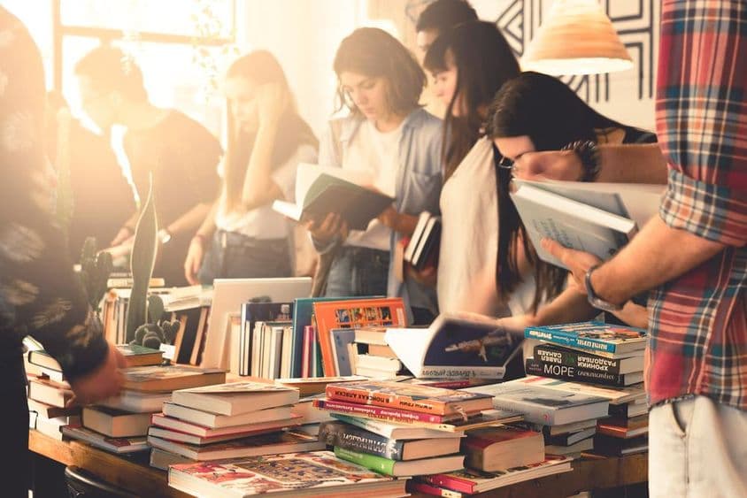 طلباء ایک بڑے کتاب میلے میں کتابیں دیکھ رہے ہیں۔