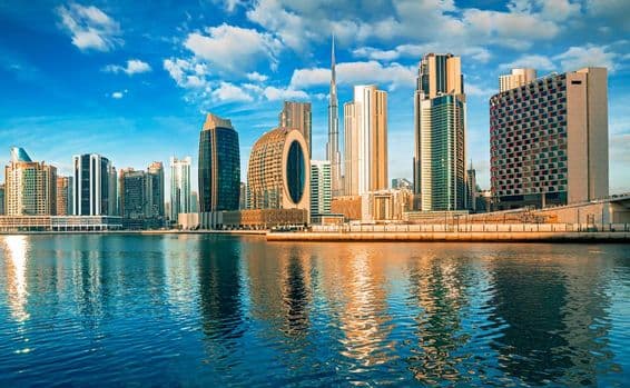 پانی کے سامنے دبئی کی فلک بوس عمارتیں، پس منظر میں برج خلیفہ