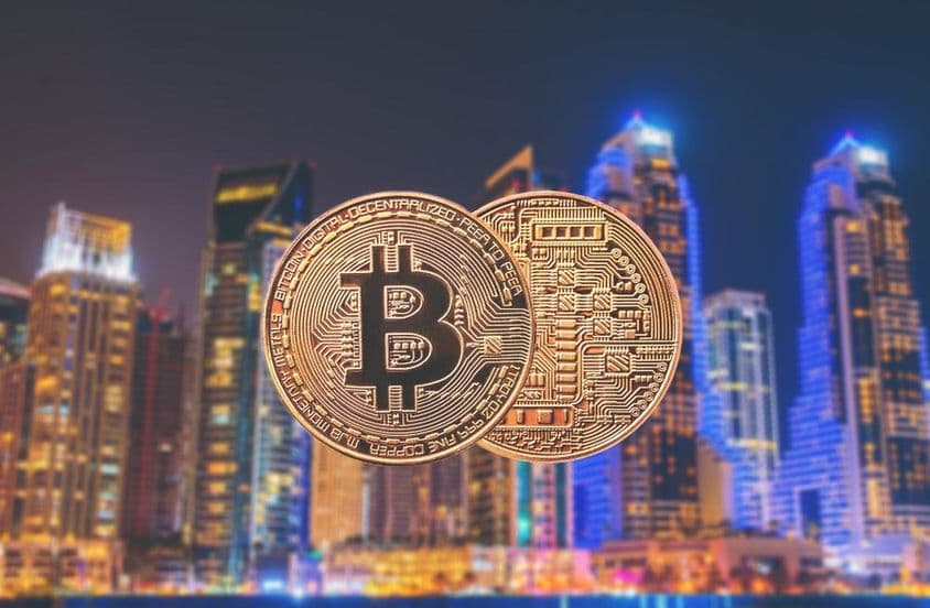 سامنے بٹ کوائن کے سکے اور پس منظر میں فلک بوس عمارتیں