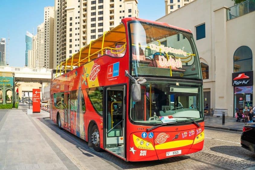 دبئی آن اور آف بس کے پس منظر میں فلک شگاف عمارتیں۔
