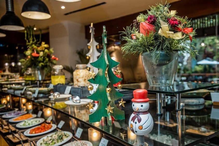 ریستوران میں سبزیوں کے کاؤنٹر پر ایک چھوٹا سا سنومین، لکڑی کے کرسمس ٹری کے ساتھ۔