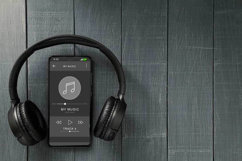 موسیقی کی چلتا ہوئی پلے بیک، ایک فون پر، ساتھ ہی ہیڈفون موجود ہیں۔