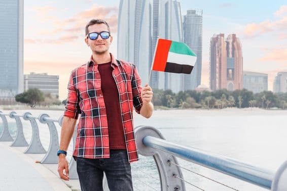 دبئی مرینا میں ایک نوجوان اماراتی جھنڈا اٹھائے ہوئے ہے۔