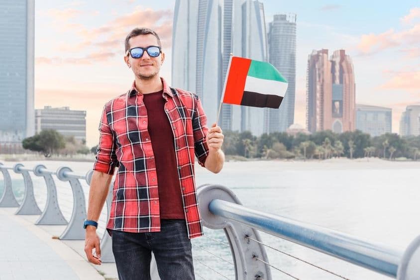 دبئی مرینا میں ایک نوجوان اماراتی جھنڈا اٹھائے ہوئے ہے۔