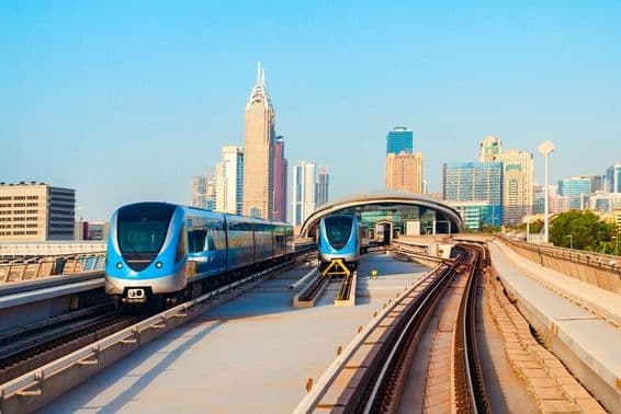 دبئی میٹرو کی گاڑیاں پس منظر میں بلند عمارتوں کے ساتھ۔