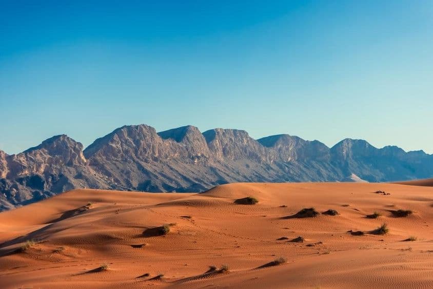پس منظر میں پہاڑوں کے ساتھ یو اے ای کا صحرا