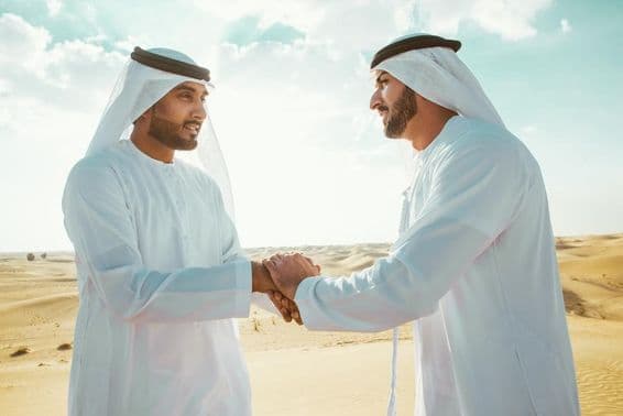 صحرا میں دو عرب مرد ہاتھ ملاتے ہوئے