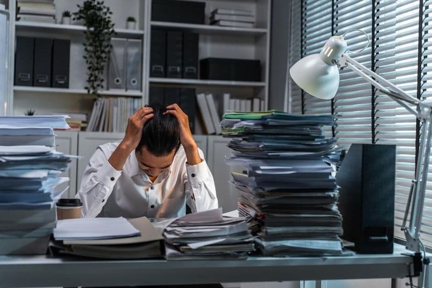 دفتر کا کارکن بے پناہ کام کے تحت سر پکڑے ہوئے ہے۔