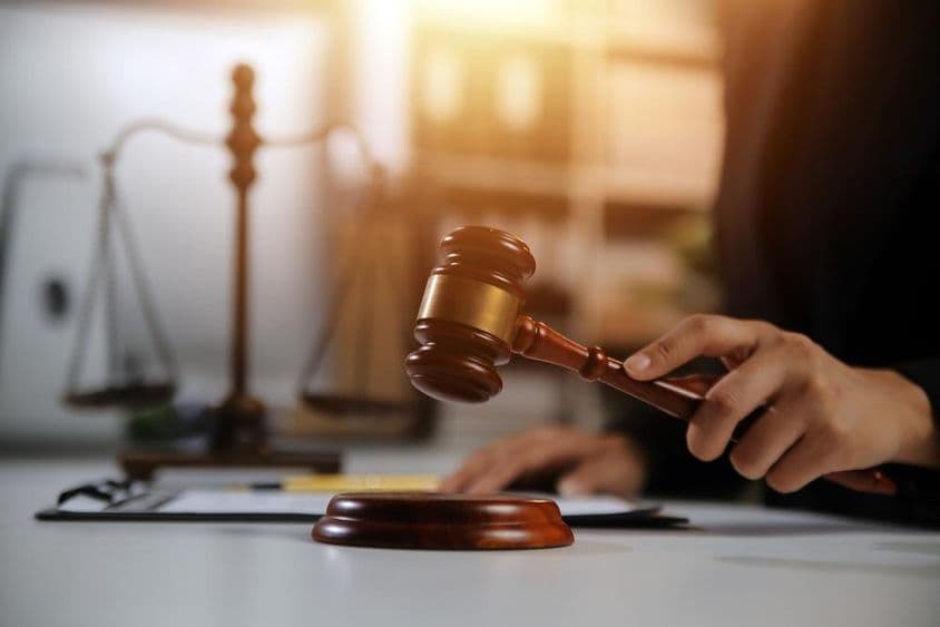 جج کے ہاتھ میں ہتھوڑا، پس منظر میں میزان