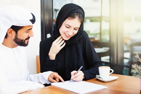 ایک عربی شخص ایک حجاب پہنی خاتون کو دستخط کے لئے دستاویزات دے رہا ہے