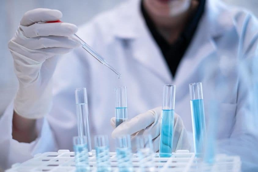 محقق تجربہ گاہ میں ایک نیلی مائع کو پائپٹ کر کے ایک ٹیسٹ ٹیوب میں ڈال رہا ہے۔