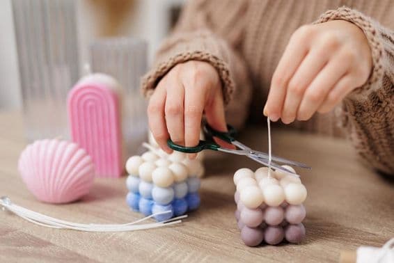 میز پر ایک بتی، چھوٹی لڑکی بتی کا بتیری کاٹ رہی ہے۔