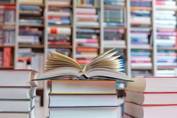 کتابوں کے ڈھیر کے اوپر کھلی ناول جو الماری کے سامنے رکھی ہے۔