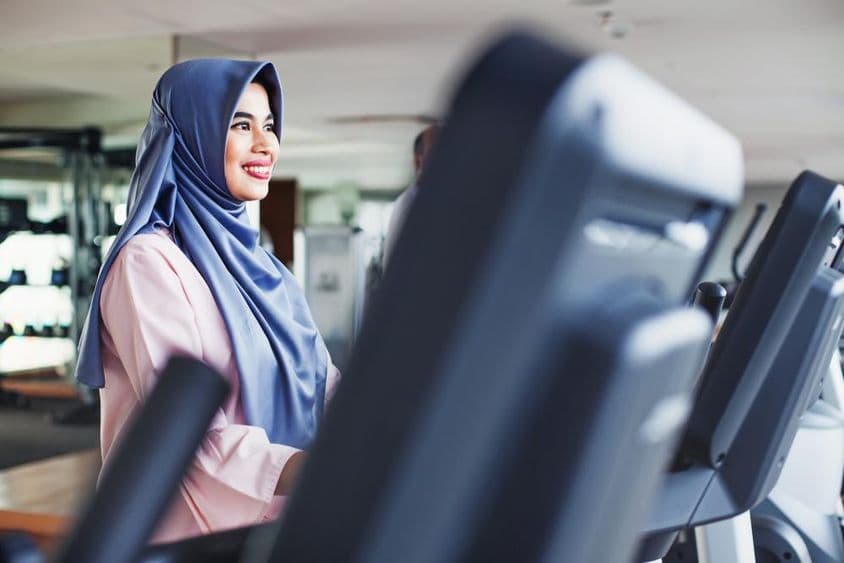 ایک مسلم خاتون جم میں ورزش کر رہی ہیں، حجاب پہنے ہوئے۔