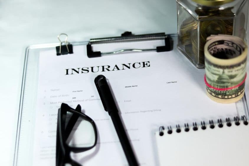 انشورنس فارم کے ساتھ سکوں کی ڈبیا، ڈالر کا گھٹنہ، قلم، اور چشمہ