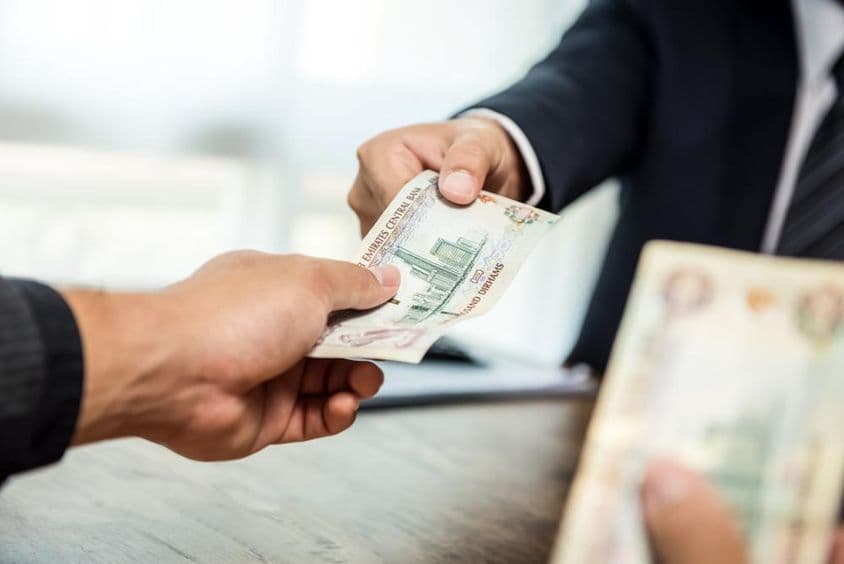 متحدہ عرب امارات کی کرنسی درہم میں پارٹنر کو رقم دیتی ہوئی کاروباری شخصیت