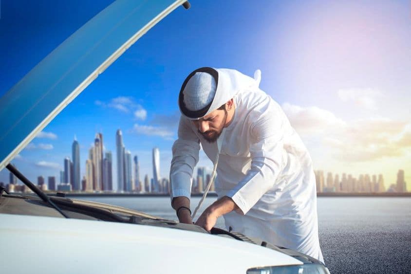 ایک عرب آدمی اپنی کار کا معائنہ کرتے ہوئے، گاڑی کا بونٹ کھلا ہوا۔