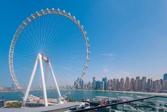 عین دبئی فیرس وہیل کے ساتھ بڑی عمارات اور سمندر پس منظر میں