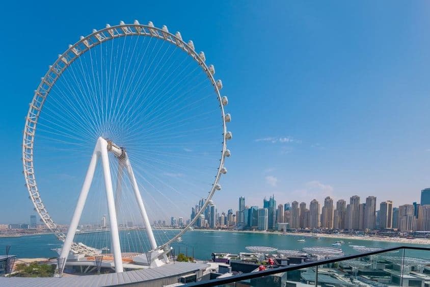 عین دبئی فیرس وہیل کے ساتھ بڑی عمارات اور سمندر پس منظر میں