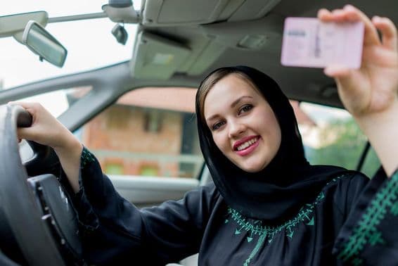 ایک مسلم خاتون گاڑی چلاتے ہوئے، لائسنس پکڑے ہوئے۔