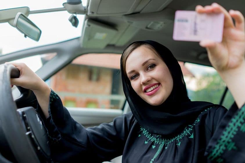 ایک مسلم خاتون گاڑی چلاتے ہوئے، لائسنس پکڑے ہوئے۔