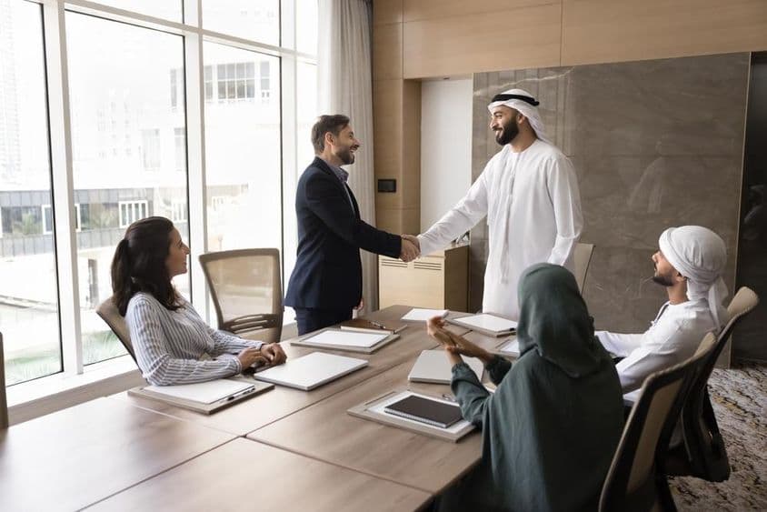 عرب اور یورپی کاروباری افراد ٹیم میٹنگ میں ہاتھ ملا رہے ہیں، کارپوریٹ گفتگو۔