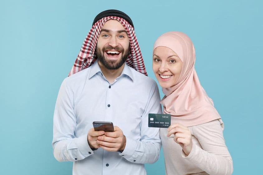مسکراتا ہوا جوڑا کریڈٹ کارڈ اور فون پکڑے ہوئے۔