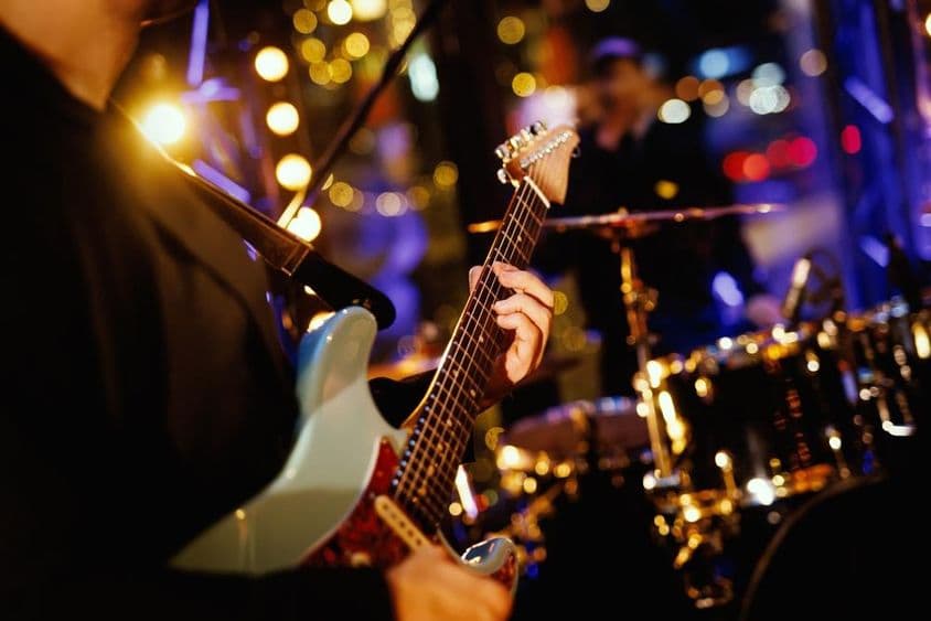 بینڈ کی کارکردگی کے دوران ایک گٹارسٹ فریٹ بورڈ پر ایک چورڈ بجاتے ہوئے۔