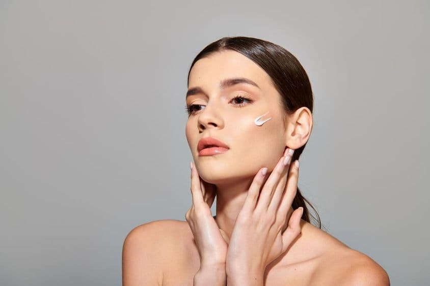 ایک نوجوان عورت اپنے چہرے پر بیوٹی کریم لگا رہی ہے، خود کا خیال رکھنے کی اہمیت ظاہر کر رہی ہے۔