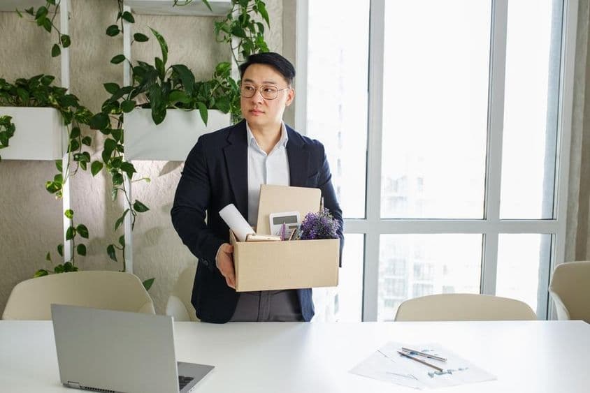 ایک آدمی اپنے کام کی جگہ سے برطرف ہو رہا ہے، اپنے ذاتی سامان کو گتے کے ڈبے میں پیک کر رہا ہے۔