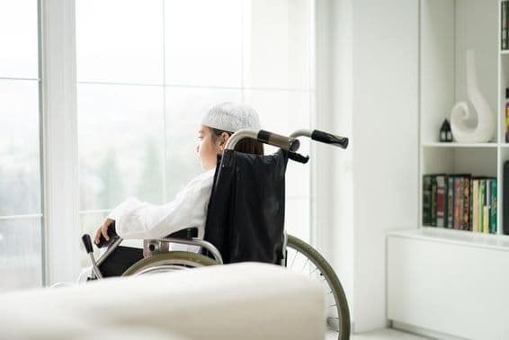 ایک جوان لڑکا وہیل چیئر میں بیٹھا ہوا کھڑکی سے باہر دیکھ رہا ہے۔