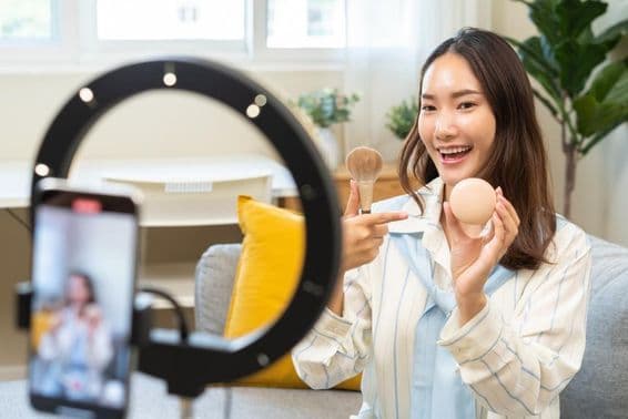 نوجوان انفلوینسر عورت بلاگر اسمارٹ فون کے ذریعے ویڈیو اسٹریمنگ پوڈکاسٹ میں بولتی ہوئی۔