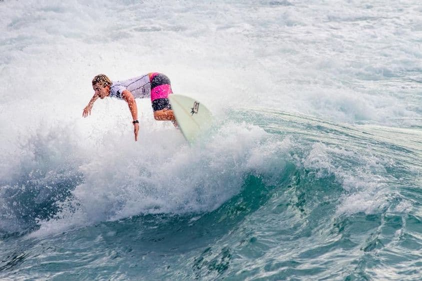 ایک نوجوان لڑکا بڑی لہر پر سرفنگ کر رہا ہے۔