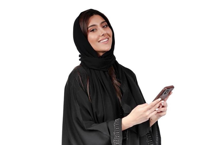 عرب عبایا میں موبائل فون پر کام کرنے والی اماراتی کاروباری خاتون۔