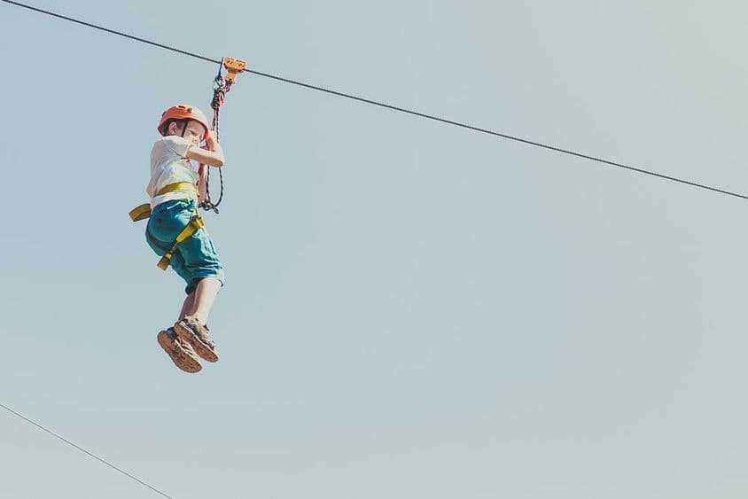 ایک لڑکا ایڈونچر پارک میں گرمائی دھوپ کے دن چڑھ رہا ہے۔