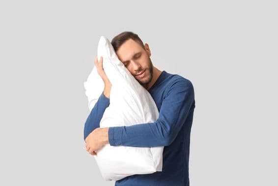 پیجامے میں نوجوان اپنے نرم تکیے کے ساتھ۔