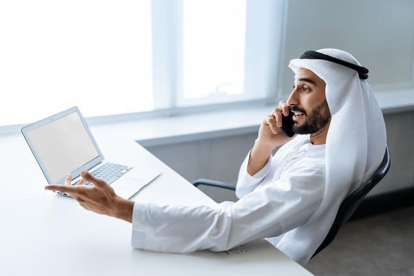 روایتی اماراتی سفید لباس میں دبئی میں کام کرنے والا کامیاب کاروباری آدمی۔