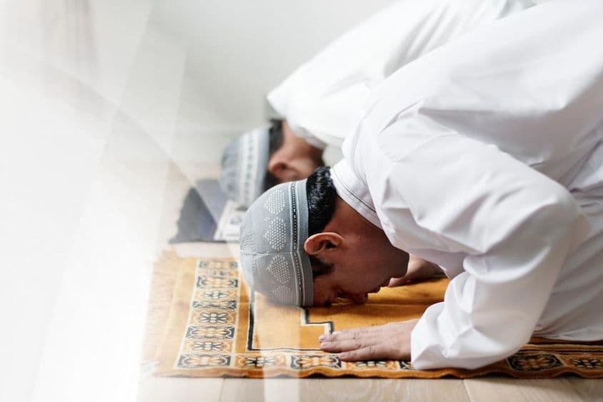 سفید لباس میں اسلامی مرد نماز میں رکوع کرتے ہوئے۔