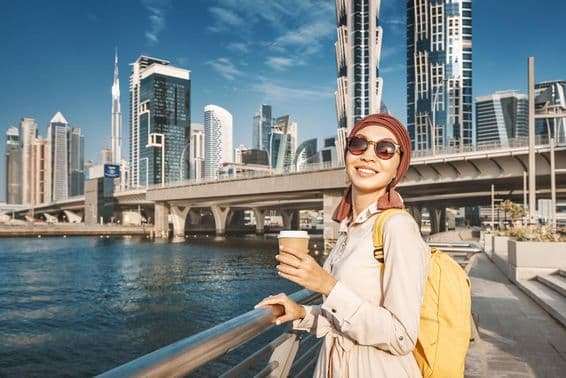 دبئی کینال کے پاس زرد بیگ کے ساتھ چلتی ہوئی مسلم خاتون