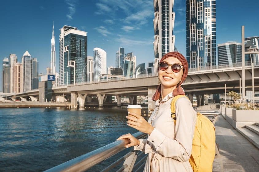 دبئی کینال کے پاس زرد بیگ کے ساتھ چلتی ہوئی مسلم خاتون