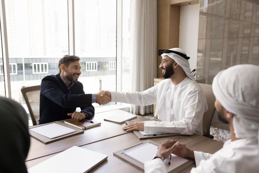 ملٹی نیشنل کاروباری پارٹنرز ایک کامیاب مذاکرہ ختم کرتے ہوئے مصافحہ کرتے ہیں۔