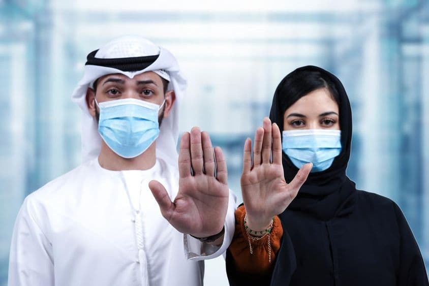 عرب مرد اور خاتون طبی ماسک پہنے ہوئے روکنے کا اشارہ کرتے ہوئے
