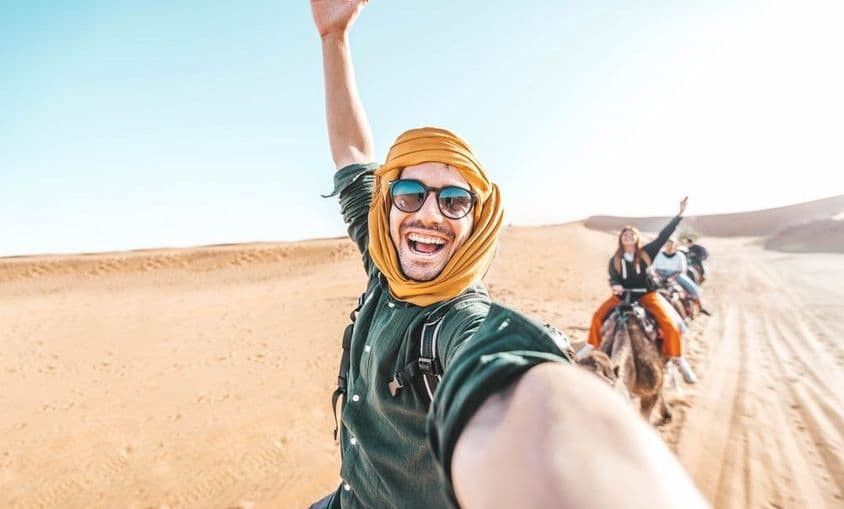 خوش سیاح صحرا میں اونٹ کی سواری کرتے ہوئے لطف اندوز ہو رہا ہے۔