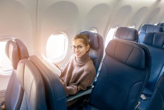 ایک ایشیائی خاتون جہاز میں میگزین پڑھ رہی ہیں۔