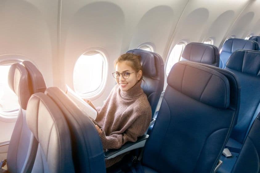 ایک ایشیائی خاتون جہاز میں میگزین پڑھ رہی ہیں۔