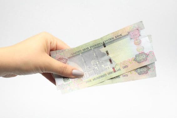 ایک عورت کے ہاتھ میں ٥٠٠ اے ای ڈی کرنسی۔