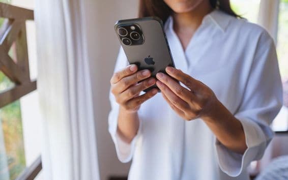 ایک عورت گھر میں آئی فون 15 پرو میکس کا استعمال کر رہی ہے