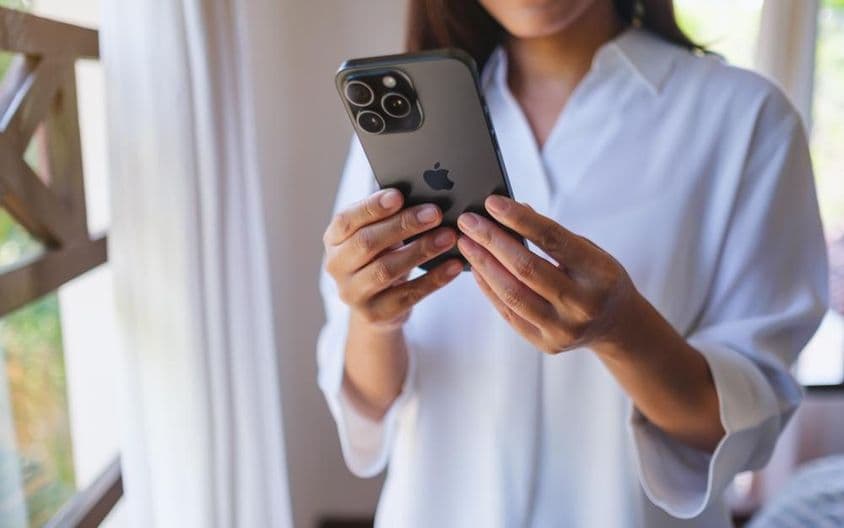 ایک عورت گھر میں آئی فون 15 پرو میکس کا استعمال کر رہی ہے